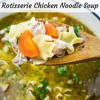 Wooden spoon with Rotisserie chicken noodle soup, featuring noodles, chicken pieces, and carrots, over a pot filled with broth and garnished with herbs.