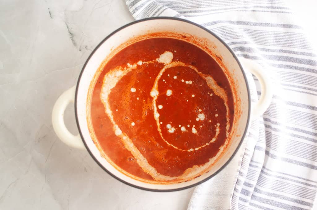 Overhead shot of creamy tomato soup with a swirl of cream.