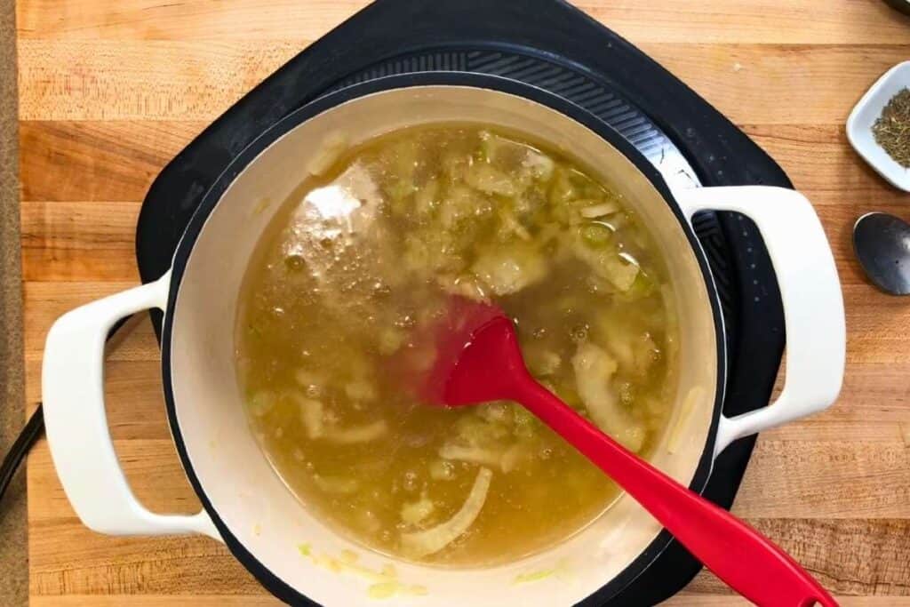 Pour in the white wine and use a wooden spoon to scrape up any browned bits from the bottom of the pot.